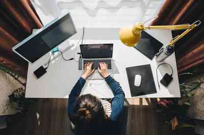 Frau sitzt im Homeoffice beim Schreibtisch und arbeitet am Laptop
